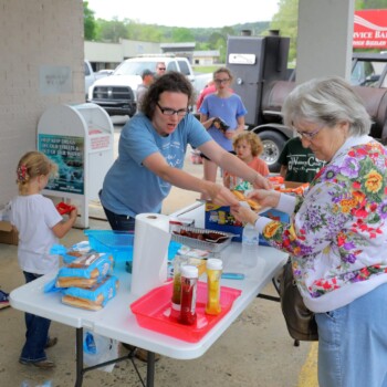 Wesley Potts, left, (dark blue shirt, kaki pants, badge) with the 20th judicial District Drug Task Force chats with parents and children at a Drug Take Back event site Saturday morning in Clinton. Potts, along with members of the Van Buren County Sheriff’s Department provided hot dog, snacks and drinks to passersby.